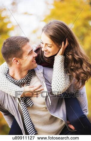 Man giving piggy back ride to woman in park View Large Photo Image Stock Photo - Man giving piggy back ride to woman in park. Fotosearch