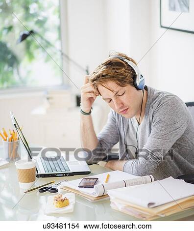 Man listening to music in home office View Large Photo Image Picture - Man listening to music in home office. Fotosearch