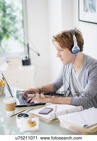 Stock Image - Man multi-tasking in home office. Fotosearch