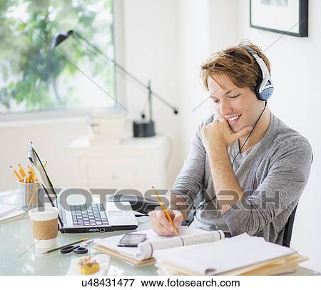 Stock Photo - Man multi-tasking in home office. Fotosearch