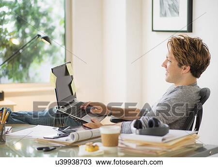 Man using laptop in home office View Large Photo Image Stock Image - Man using laptop in home office. Fotosearch