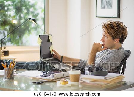 Man using laptop in home office View Large Photo Image Stock Photo - Man using laptop in home office. Fotosearch