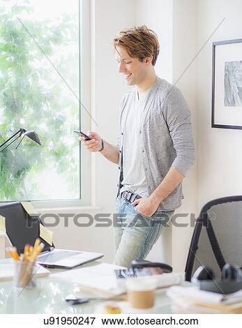 Stock Photo - Man using phone in home office. Fotosearch