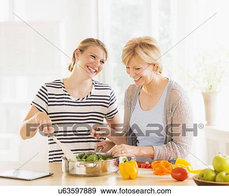 Mother and adult daughter cooking together View Large Photo Image Stock Photo - Mother and adult daughter cooking together. Fotosearch
