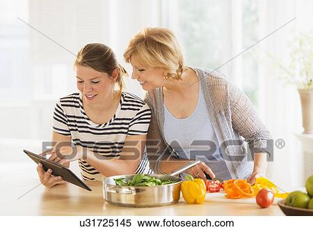 Mother and adult daughter cooking together using tablet pc View Large Photo Image Stock Photography - Mother and adult daughter cooking together using tablet pc. Fotosearch