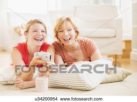 Mother and adult daughter relaxing at home, watching tv View Large Photo Image Picture - Mother and adult daughter relaxing at home, watching tv. Fotosearch