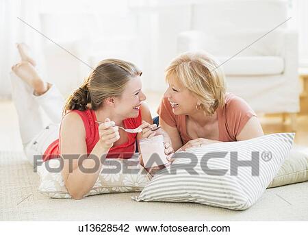 Mother and adult daughter relaxing at home, eating ice cream View Large Photo Image Stock Image - Mother and adult daughter relaxing at home, eating ice cream. Fotosearch