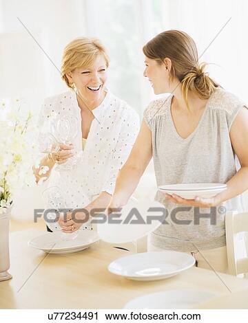 Mother and adult daughter setting table for dinner View Large Photo Image Stock Image - Mother and adult daughter setting table for dinner. Fotosearch