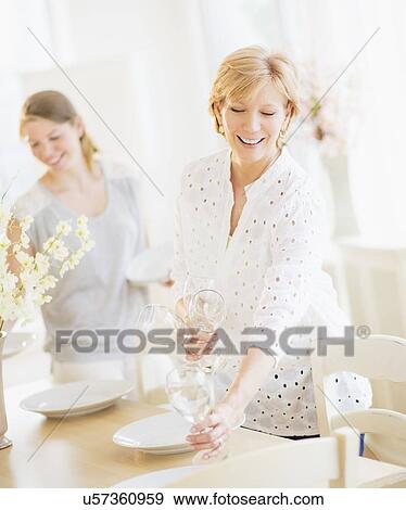 Mother and adult daughter setting table for dinner View Large Photo Image Stock Photo - Mother and adult daughter setting table for dinner. Fotosearch