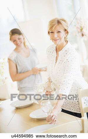 Mother and adult daughter setting table for dinner View Large Photo Image Stock Photography - Mother and adult daughter setting table for dinner. Fotosearch