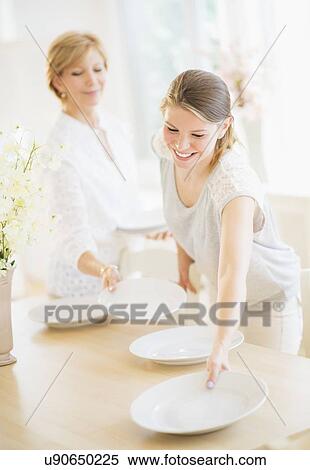 Mother and adult daughter setting table for dinner View Large Photo Image Stock Photography - Mother and adult daughter setting table for dinner. Fotosearch