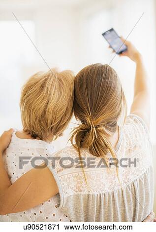 Stock Image - Mother and adult daughter taking self-portrait with smartphone. Fotosearch