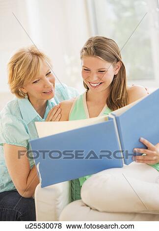 Stock Photo - Mother and adult daughter watching photo album. Fotosearch