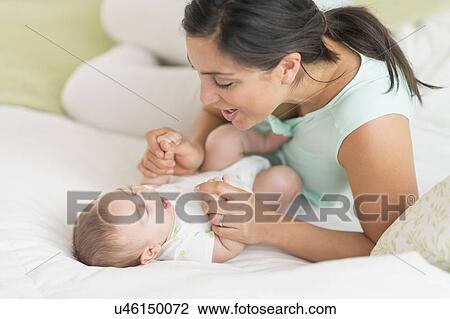 Mother and baby (2-5 months) lying on bed View Large Photo Image Stock Image - Mother and baby (2-5 months) lying on bed. Fotosearch