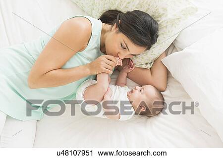 Mother and baby (2-5 months) lying on bed View Large Photo Image Stock Image - Mother and baby (2-5 months) lying on bed. Fotosearch