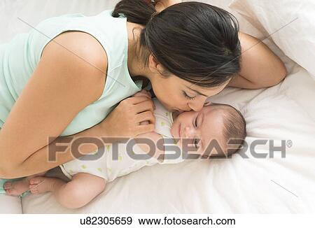 Mother and baby (2-5 months) lying on bed View Large Photo Image Stock Photo - Mother and baby (2-5 months) lying on bed. Fotosearch