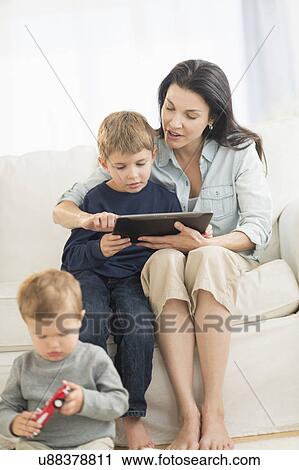 Stock Image - Mother and sons (12-17 months, 6-7) with tablet pc. Fotosearch