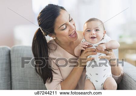 Stock Image - Mother holding baby boy (2-5 months) . Fotosearch