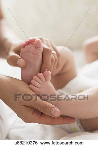 Stock Photograph - Mother holding feet of baby boy (2-5 months). Fotosearch
