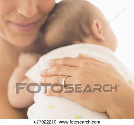 Stock Image - Mother hugging baby boy (2-5 months). Fotosearch