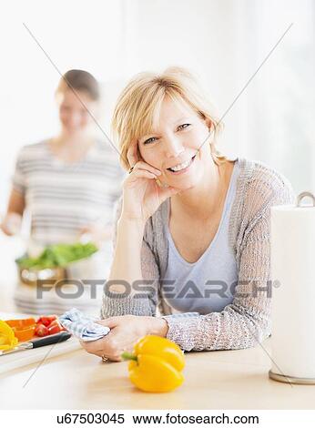 Mother leaning on kitchen counter, out-of-focus daughter in background View Large Photo Image Stock Photography - Mother leaning on kitchen counter, out-of-focus daughter in background. Fotosearch