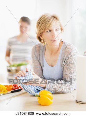 Mother leaning on kitchen counter, out-of-focus daughter in background View Large Photo Image Stock Photography - Mother leaning on kitchen counter, out-of-focus daughter in background. Fotosearch
