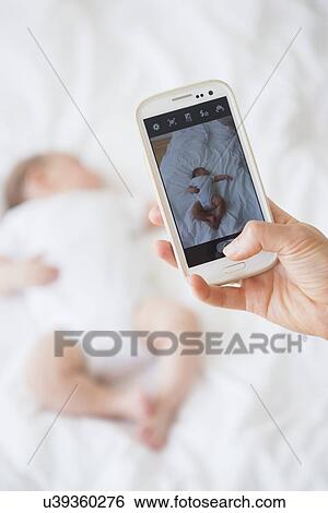 Mother photographing baby girl (2-5 months) sleeping in bed View Large Photo Image Stock Photograph - Mother photographing baby girl (2-5 months) sleeping in bed. Fotosearch