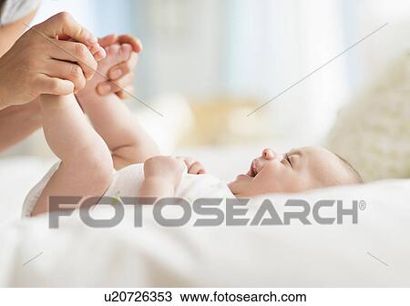 Stock Image - Mother playing with baby boy (2-5 months). Fotosearch