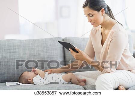 Mother playing with baby boy (2-5 months) and using digital tablet View Large Photo Image Stock Photo - Mother playing with baby boy (2-5 months) and using digital tablet. Fotosearch