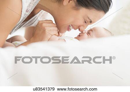 Stock Photo - Mother playing with baby boy (2-5 months). Fotosearch
