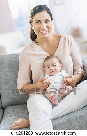 Stock Image - Mother with baby boy (2-5 months) sitting on sofa. Fotosearch
