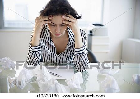 Stock Image - Overworked businesswoman sitting at desk. Fotosearch