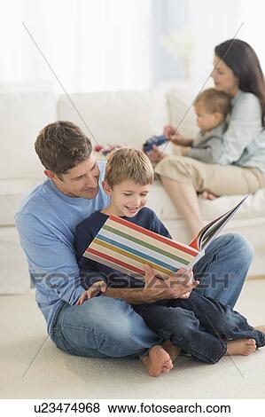 Stock Photo - Parents with kids (12-17 months, 6-7) at home, father reading to son. Fotosearch