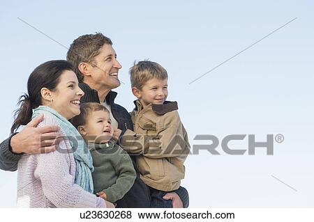 Stock Photo - Parents with kids (12-17 months, 6-7) under blue sky. Fotosearch