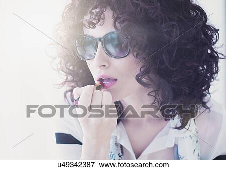 Portrait of beautiful brunette woman applying lipstick View Large Photo Image Stock Photo - Portrait of beautiful brunette woman applying lipstick. Fotosearch