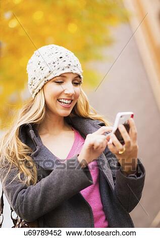 Stock Image - Portrait of blond woman using cell phone. Fotosearch
