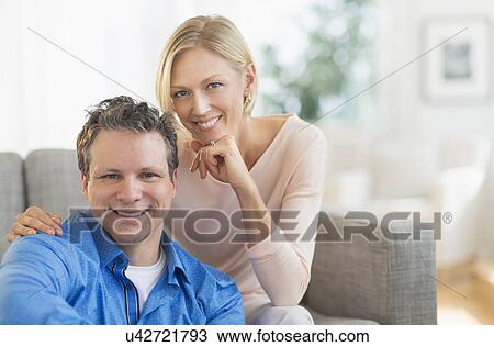 Stock Image - Portrait of couple sitting on sofa. Fotosearch