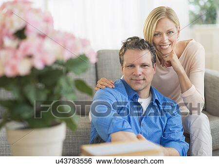 Portrait of couple sitting on sofa View Large Photo Image Stock Photograph - Portrait of couple sitting on sofa. Fotosearch