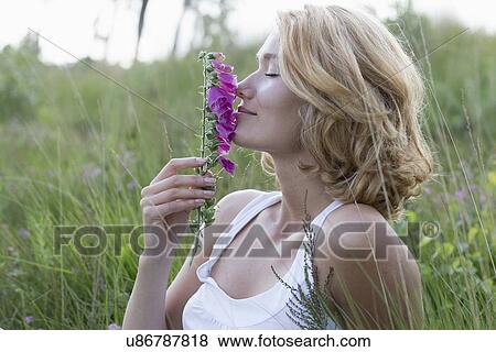 Stock Photo - Portrait of happy woman with purple flower. Fotosearch