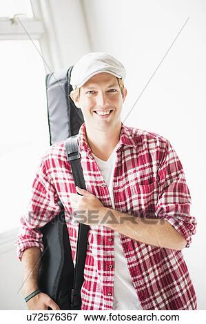 Stock Photo - Portrait of man carrying guitar bag. Fotosearch
