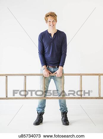 Stock Image - Portrait of man carrying ladder. Fotosearch