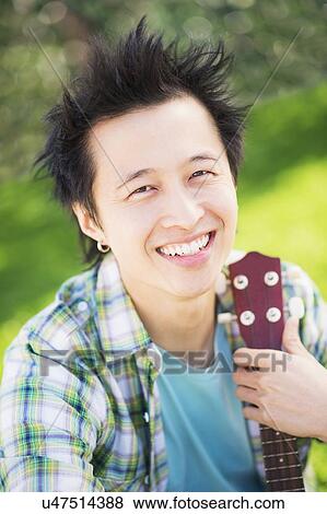 Portrait of teenage boy (16-17) playing guitar in park View Large Photo Image Stock Photo - Portrait of teenage boy (16-17) playing guitar in park. Fotosearch