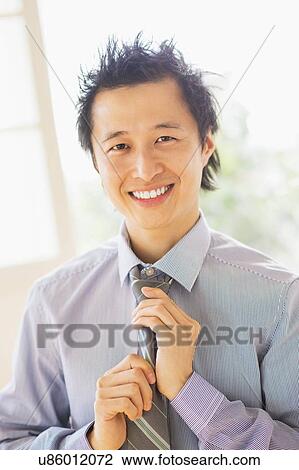 Stock Image - Portrait of teenage boy (16-17) tying tie. Fotosearch