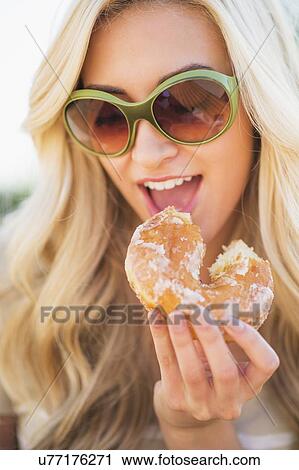 Stock Image - Portrait of teenage girl (16-17) eating doughnut. Fotosearch
