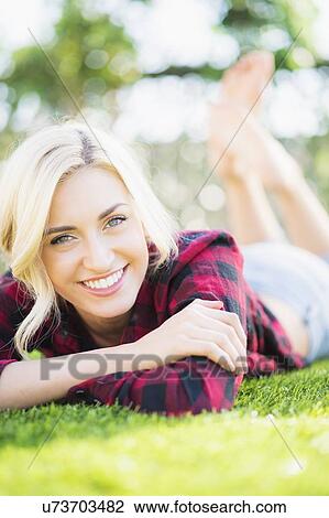 Stock Image - Portrait of teenage girl (16-17) lying on grass. Fotosearch