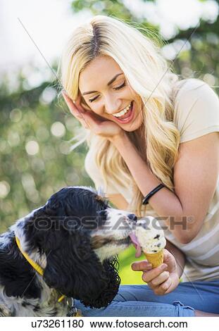 Stock Image - Portrait of teenage girl (16-17) with dog licking ice cream. Fotosearch