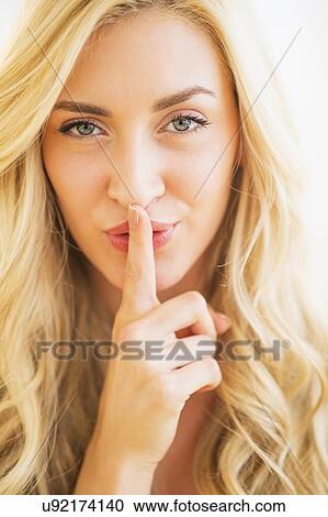 Stock Image - Portrait of teenage girl (16-17) with finger on lips. Fotosearch