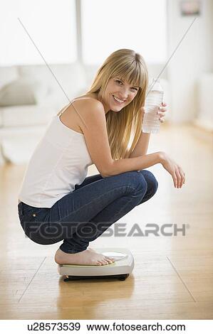 Portrait of woman crouching on weight scales View Large Photo Image Stock Photo - Portrait of woman crouching on weight scales. Fotosearch