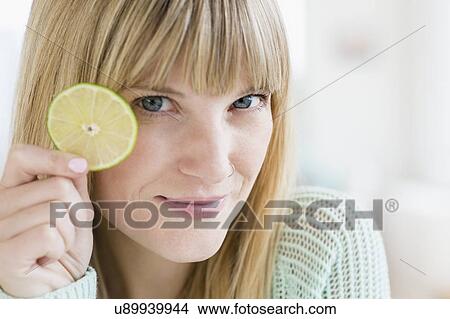 Picture - Portrait of woman holding slice of lime. Fotosearch
