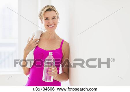 Stock Photograph - Portrait of woman in sports clothing holding water bottle. Fotosearch